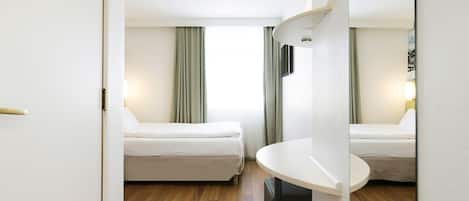 Una habitación de hotel con dos camas, un baño pequeño y vistas a la ciudad.