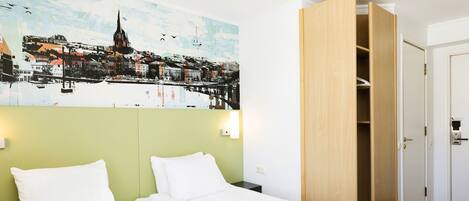 Una habitación de hotel con una cama, una mesita de noche, una lámpara de pared y un armario de madera.