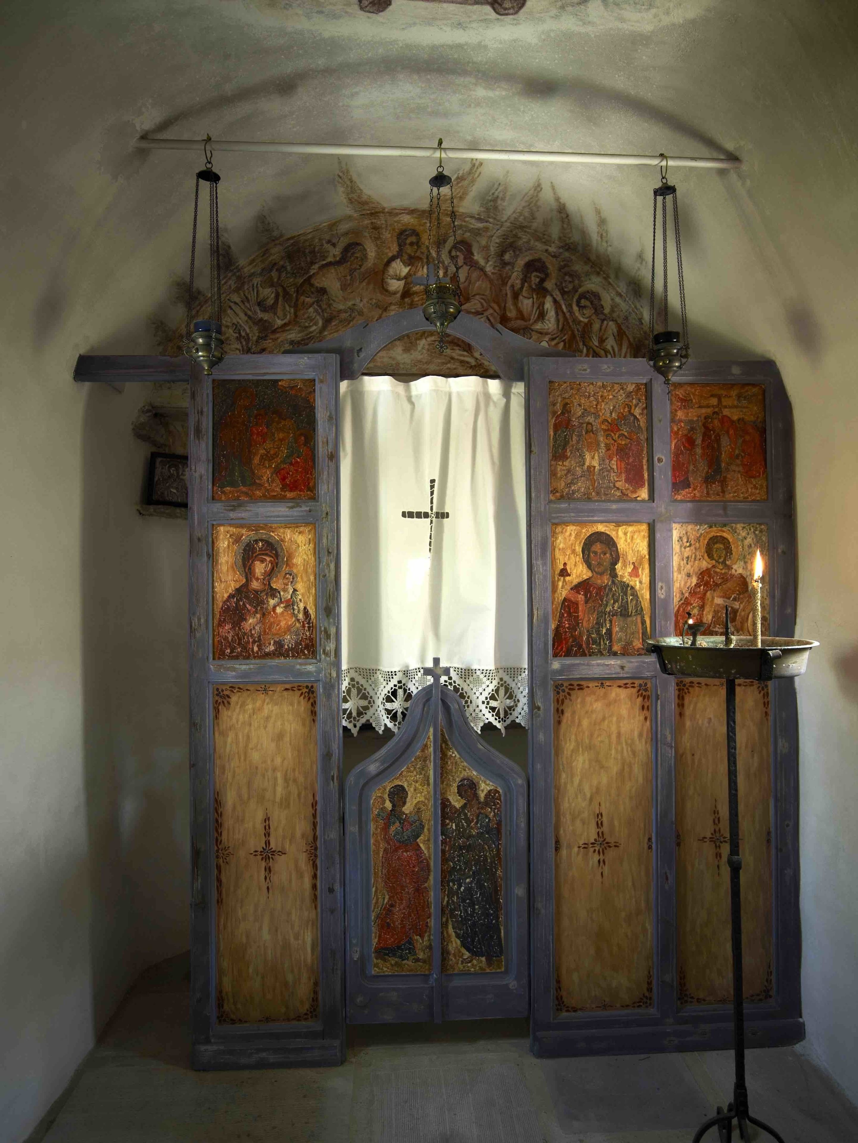 A religious iconostasis with multiple icons and a candle holder.