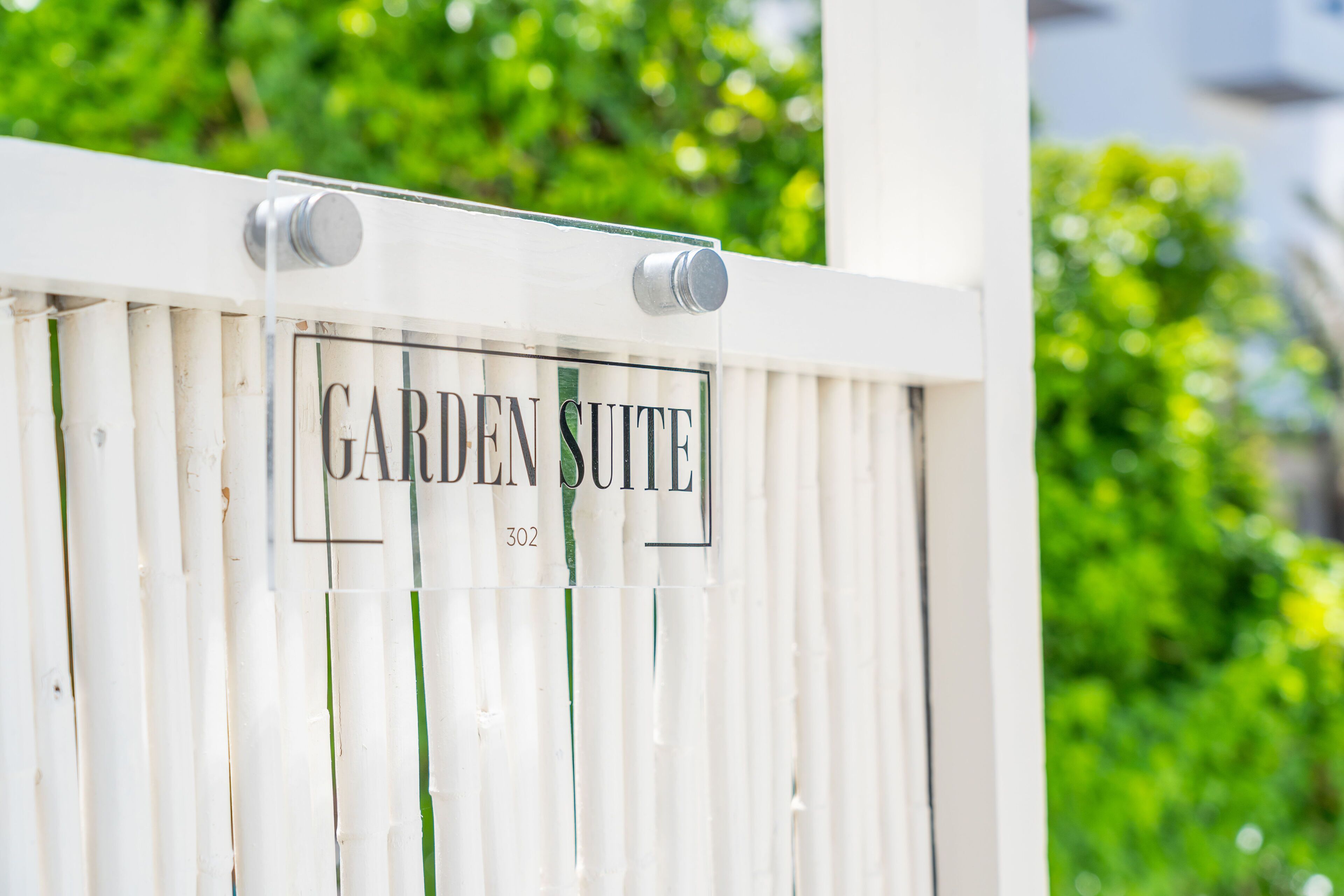 A white gate with a sign that reads "GARDEN SUITE 302".