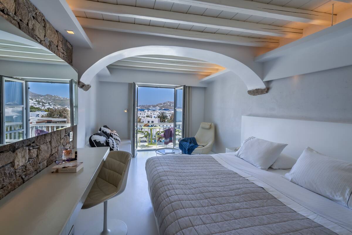 Una habitación de hotel moderna con una cama grande, un escritorio y vistas a la ciudad.