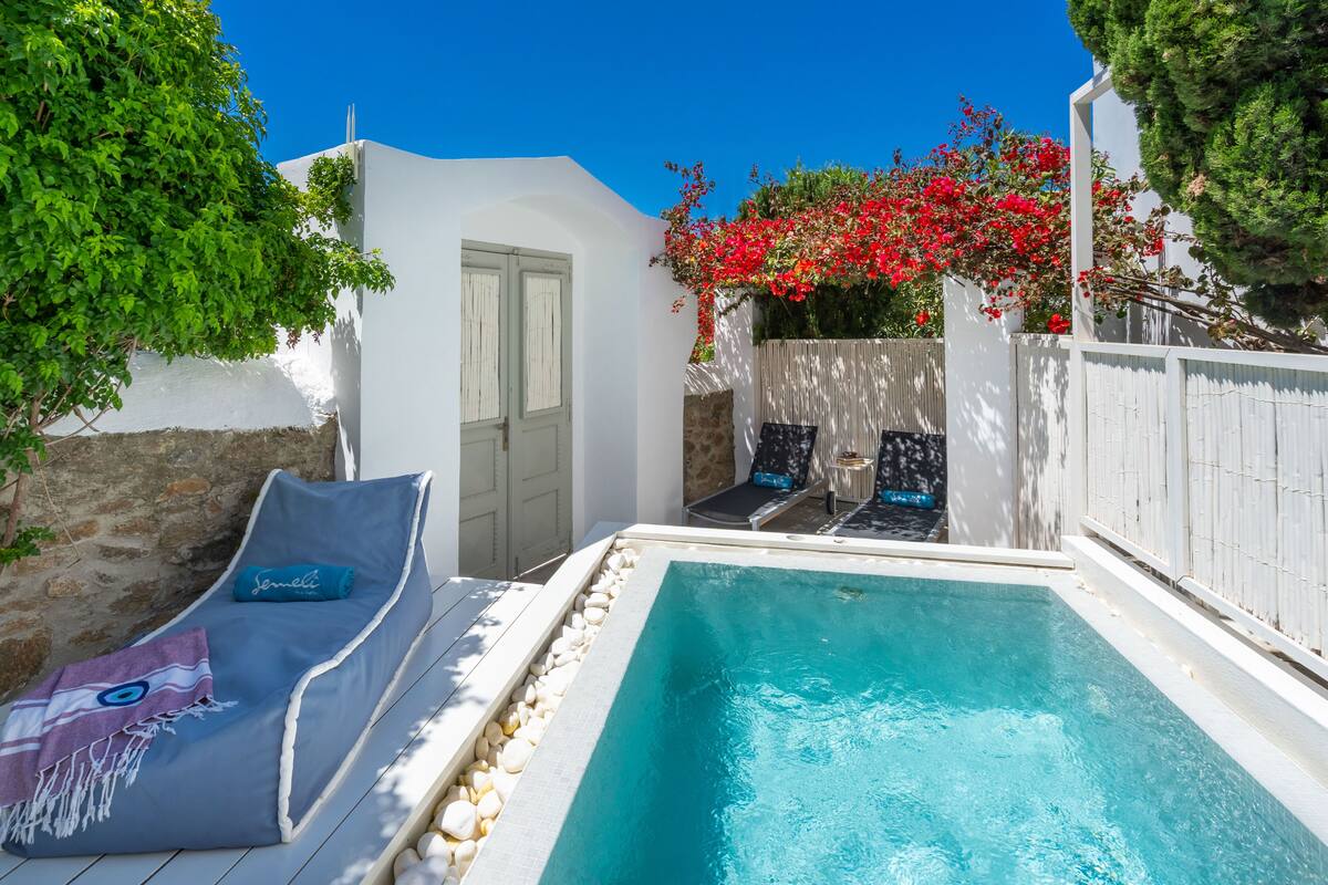 Un área de piscina con una silla de descanso, una mesita y una puerta.