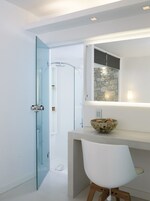 Un baño moderno con cabina de ducha de vidrio, pared decorativa de piedra y tocador blanco con un cuenco de huevos.