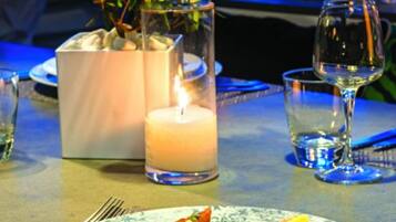 Une table à manger avec une assiette de nourriture, une bougie et un verre d’eau.