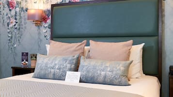 A neatly made bed with a headboard, multiple pillows, and a wall-mounted lamp.