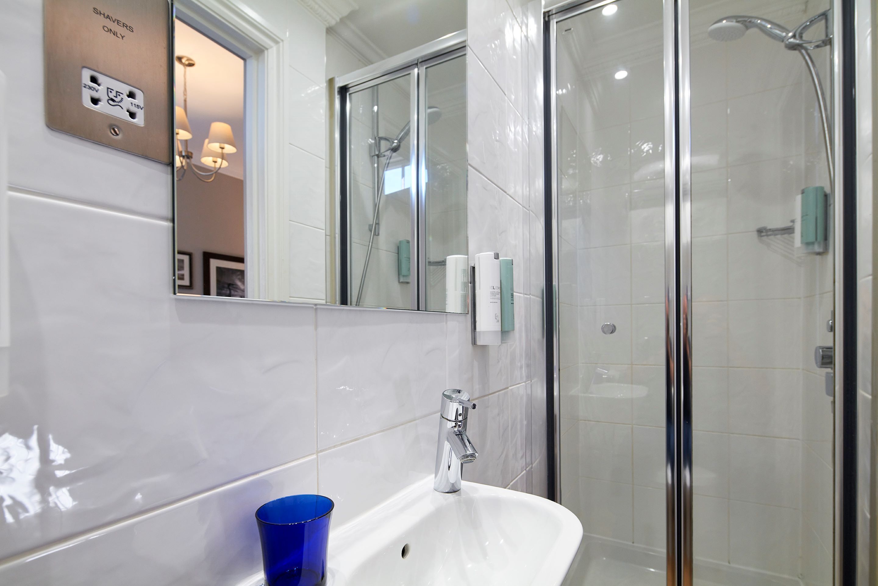 A modern bathroom with a white sink, a glass shower enclosure, and a mirror above the sink.