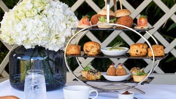 A three-tiered dessert stand with various pastries and a vase of white flowers.