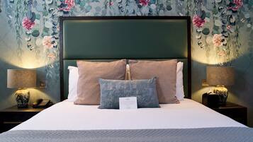 A neatly made bed with a green headboard, two pillows, and a bedside lamp on each side.