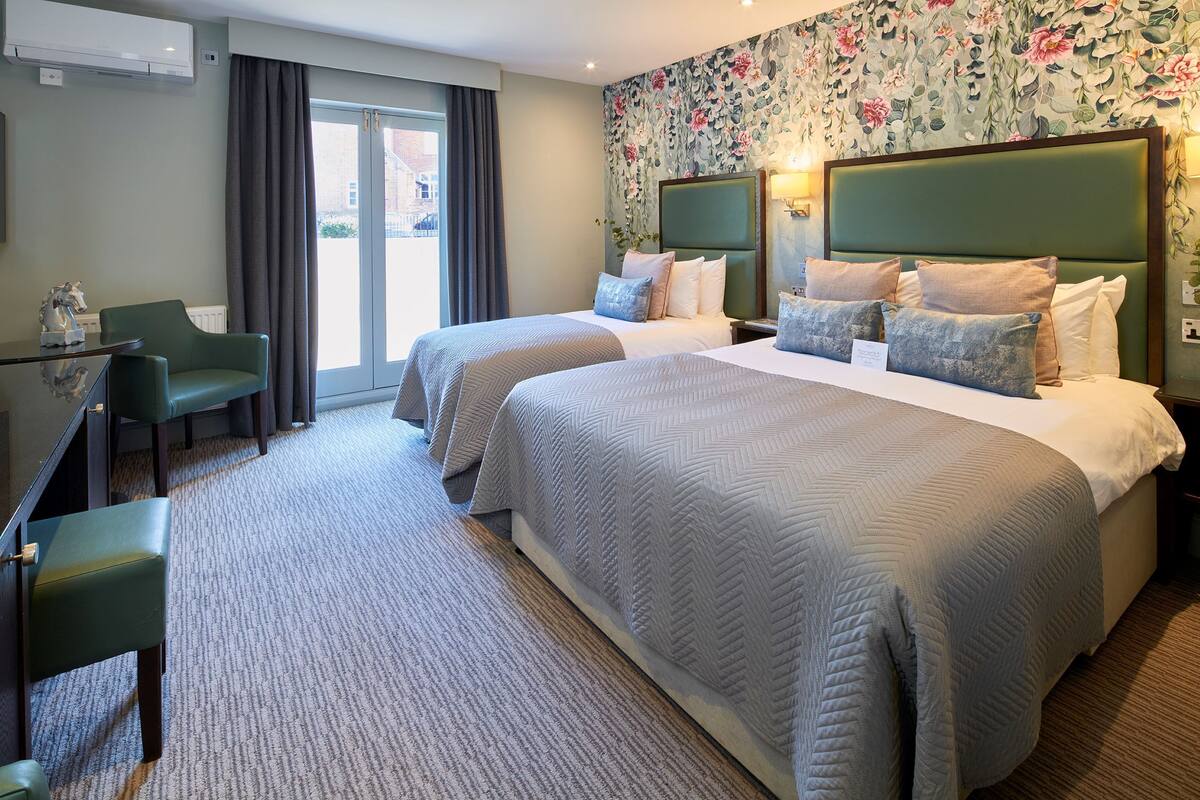 A hotel room with two beds, a desk, and a chair.