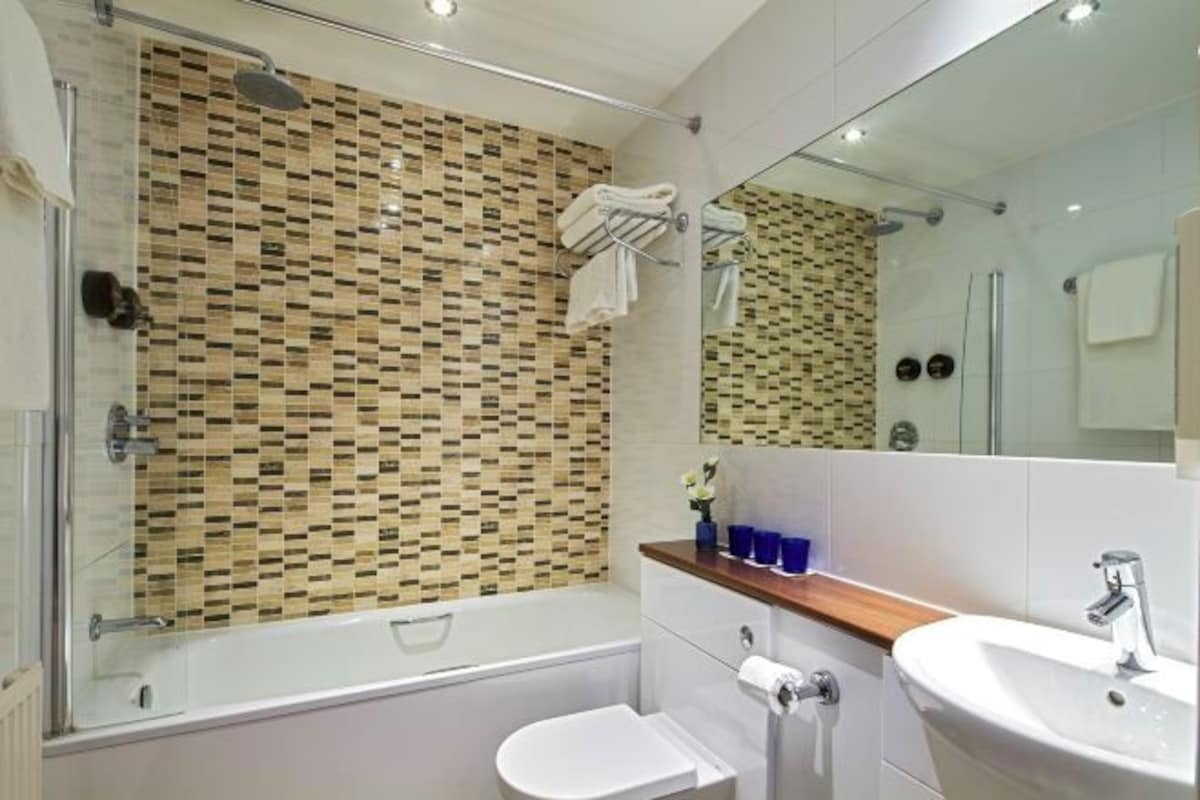 A modern bathroom with a shower, bathtub, toilet, and sink.