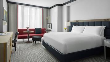 Une chambre d’hôtel avec un grand lit, un bureau, une chaise, une petite table ronde et un canapé.