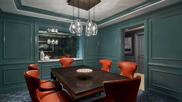 A dining area with a dark wooden table, six red chairs, and a hanging light fixture.