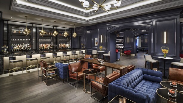 Zona de bar moderna con asientos de cuero, un candelabro y una amplia selección de licores.