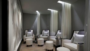 Una habitación moderna y bien iluminada con un sofá, sillas y otomanas dispuestas para relajarse.