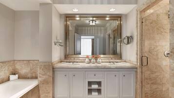 A modern bathroom with a large mirror, two sinks, a bathtub, and a walk-in shower.