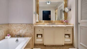 A bathroom with a bathtub, a sink with a mirror, and a vanity with drawers.