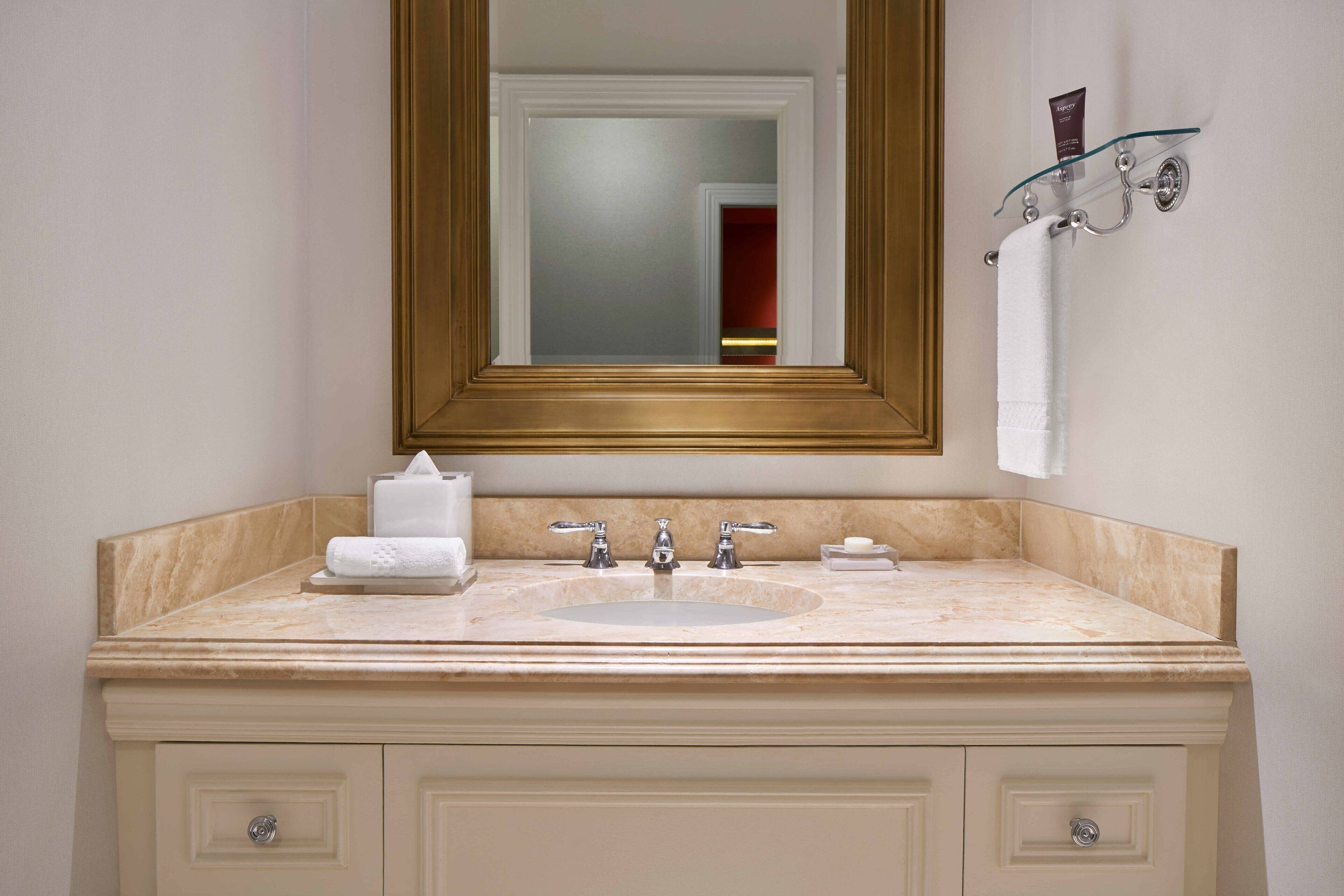 A bathroom with a marble sink, a large mirror, and a towel rack.