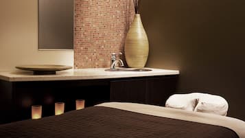 Un baño moderno con un espejo grande, un lavamanos, un florero y una cama con almohada blanca.