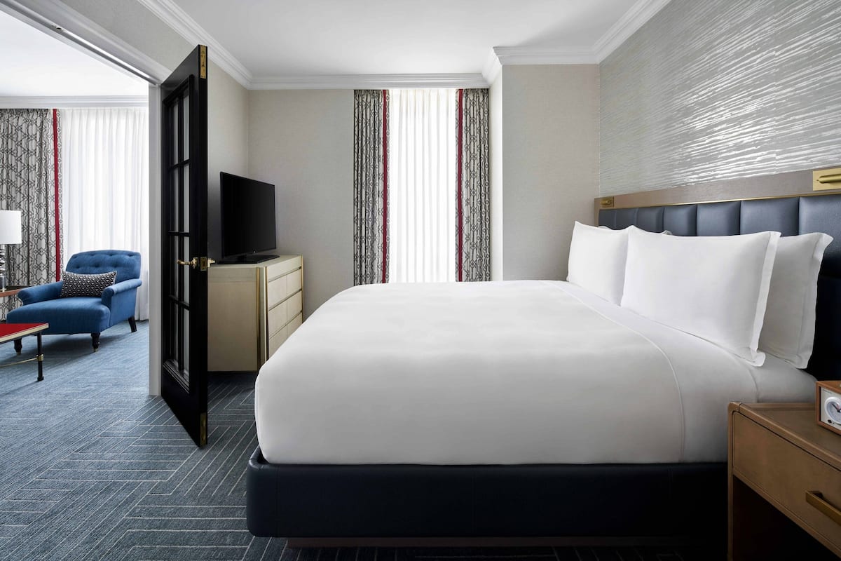 A hotel room with a large bed, a television, a desk, and a chair.