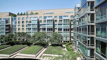 Un edificio moderno con diversi piani, ampie finestre e un cortile curato con vialetti e vegetazione.