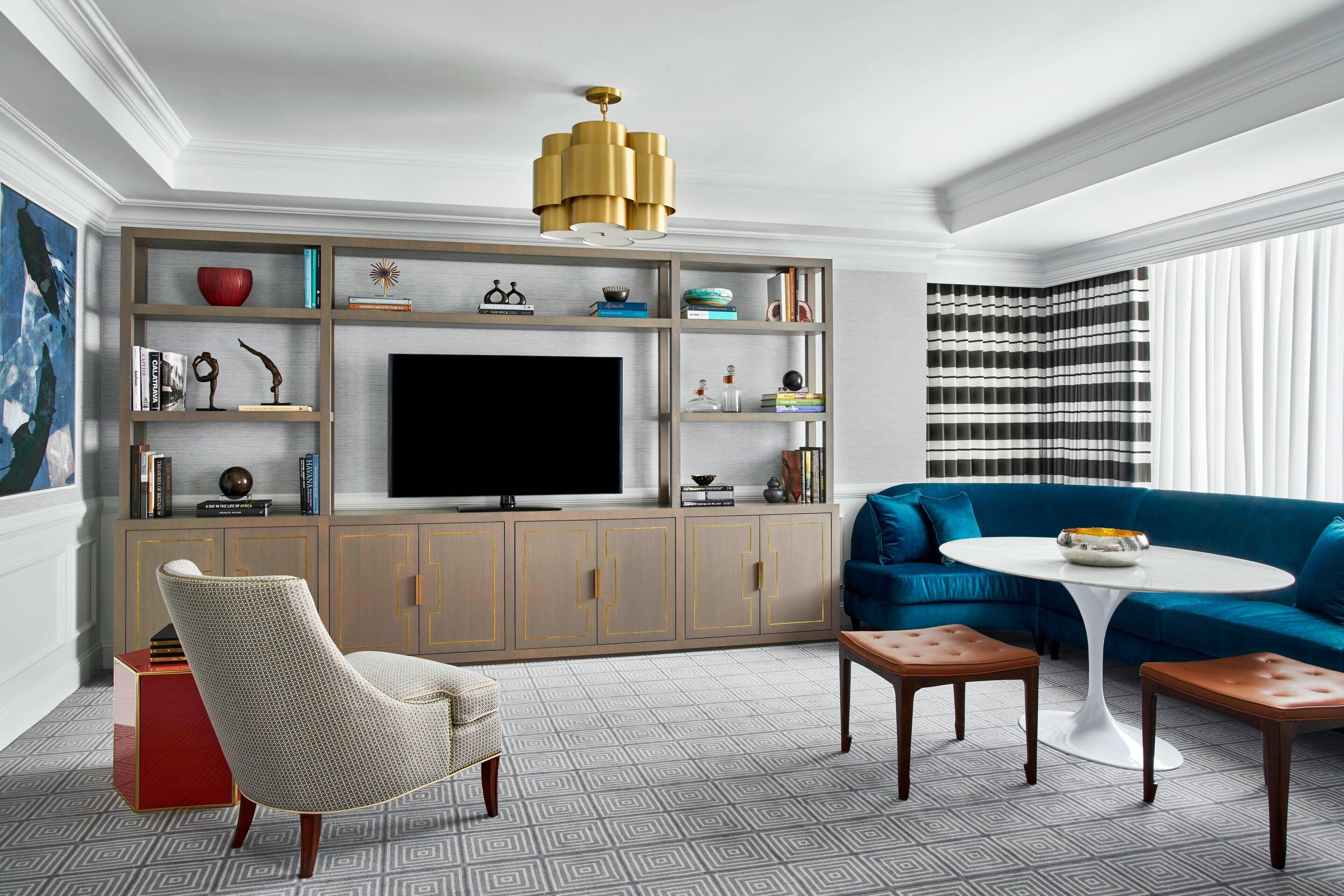 A modern living room with a large flat-screen TV, a blue sofa, a white armchair, and a round coffee table.
