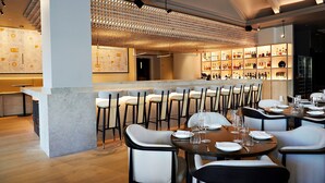 Un área de bar moderna con mostrador, asientos y una estantería para vinos.