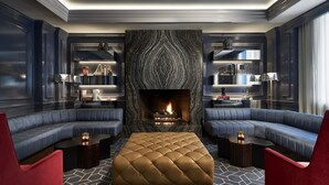 Una sala de estar moderna con chimenea, paredes oscuras y un suelo con estampado geométrico.