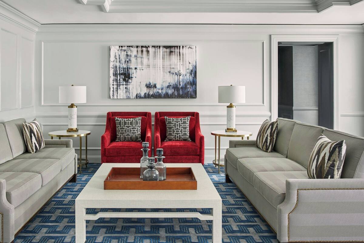 A modern living room with two sofas, a coffee table, and a large abstract painting on the wall.
