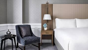 A hotel room with a bed, a chair, a nightstand, and a lamp.