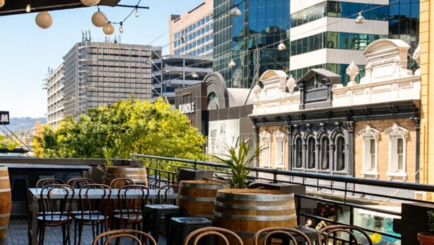 An outdoor seating area with tables and chairs, a view of modern buildings, and decorative paper lanterns. - The Richmond Hotel - Adelaide (Adelaide)