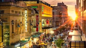 A bustling urban street scene with shops and cafes, a prominent 'REGENCY' sign, and a sunset in the background. - The Richmond Hotel - Adelaide (Adelaide)