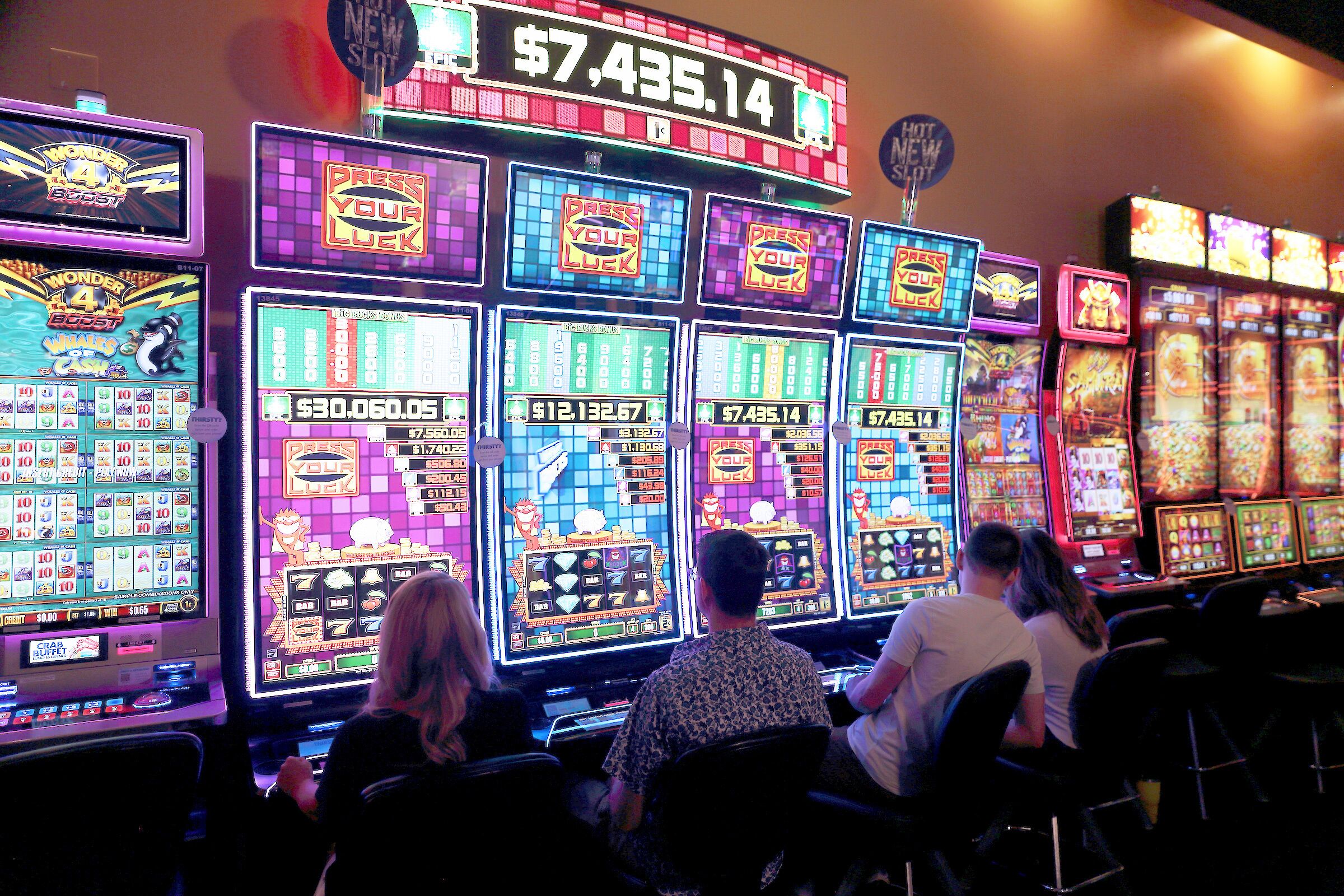 A row of slot machines with various game screens and a digital display showing $7,435.14.