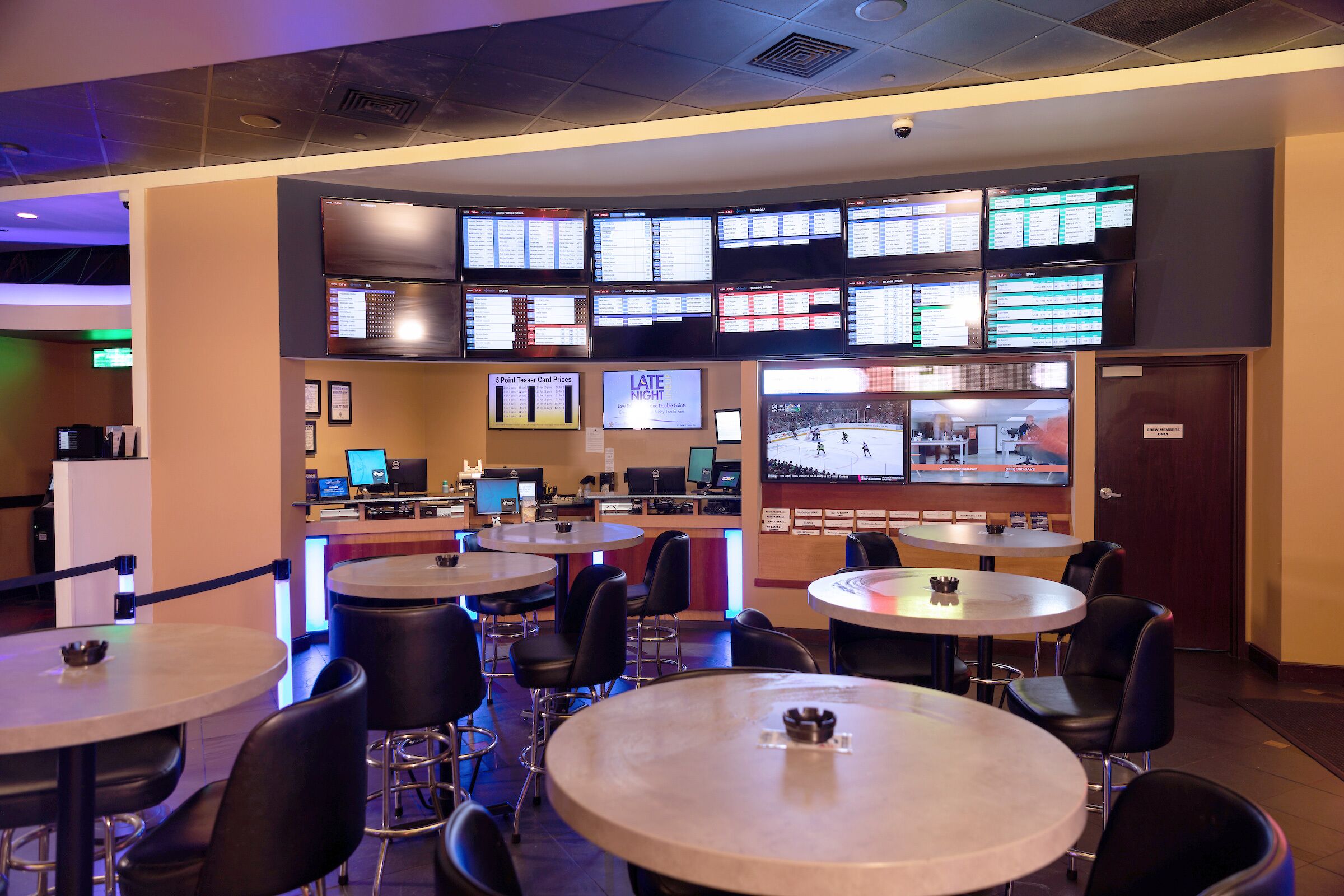 Un bar sportif doté de plusieurs écrans diffusant des programmes sportifs, avec des places assises au bar et un espace comptoir.