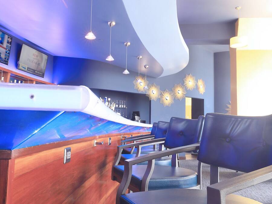 A modern bar area with a curved wooden counter, multiple seating options, and pendant lighting.