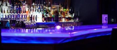 Un espace bar avec des étagères remplies de différentes bouteilles et de verres.