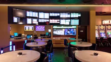 Relax and unwind in our gaming lounge, featuring multiple tables, screens, and a bar area.