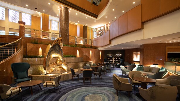 A spacious lobby with a central fountain, multiple seating areas, and a staircase leading to an upper level.