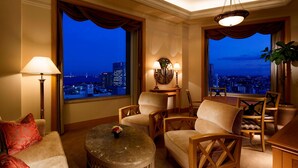 A well-lit living room with a city view, large windows, and comfortable seating.