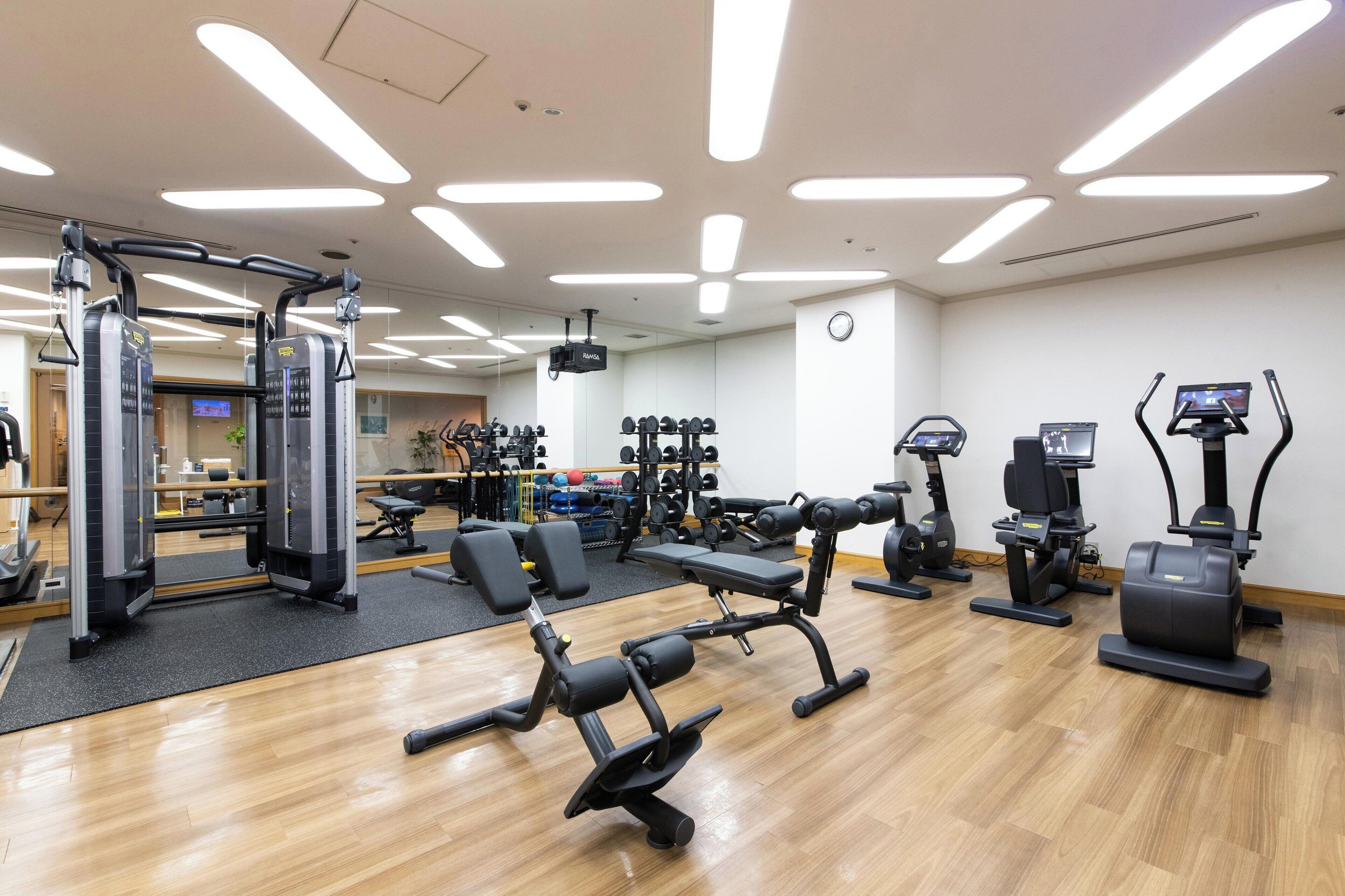 A gym with various exercise equipment, including weight machines, treadmills, and a mirror.