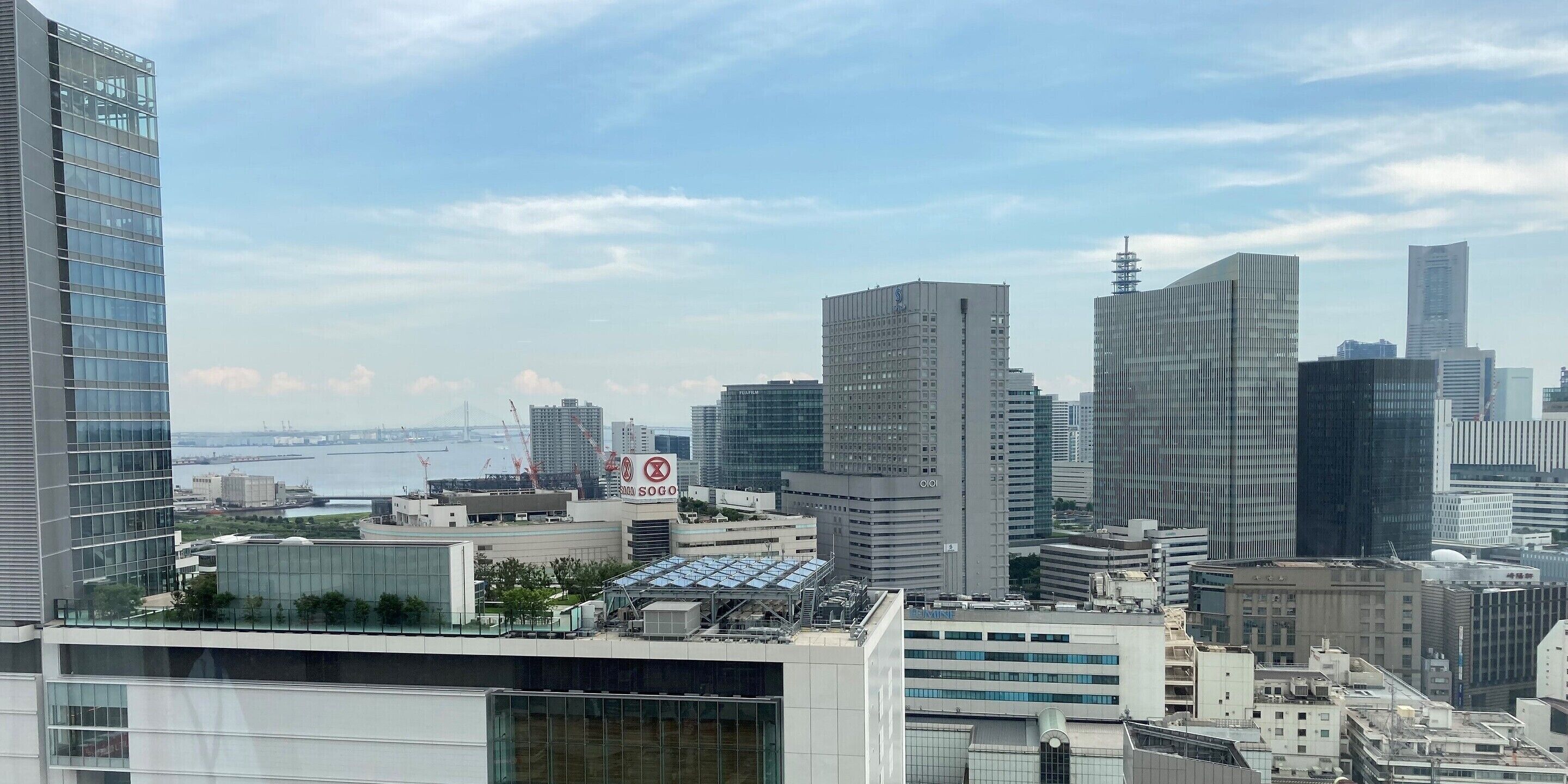 Un paisaje urbano con modernos edificios altos, un río al fondo y un puente.