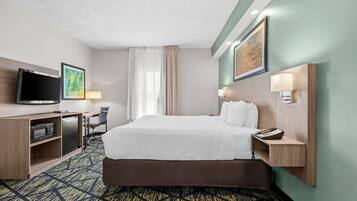 Habitación de hotel con cama, escritorio, televisor y microondas.