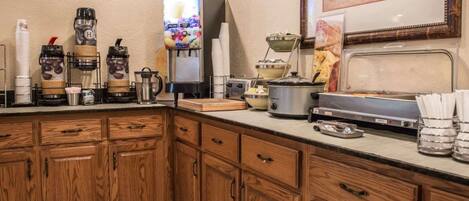 A kitchen with wooden cabinets, a coffee station, a juice dispenser, and a toaster.