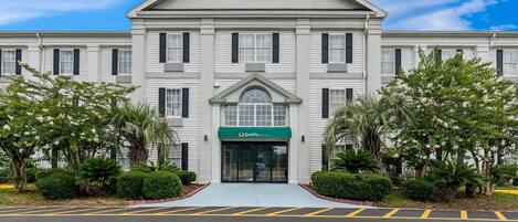 A hotel with a symmetrical facade, a central entrance, and a sign indicating it is a Choice Hotel.