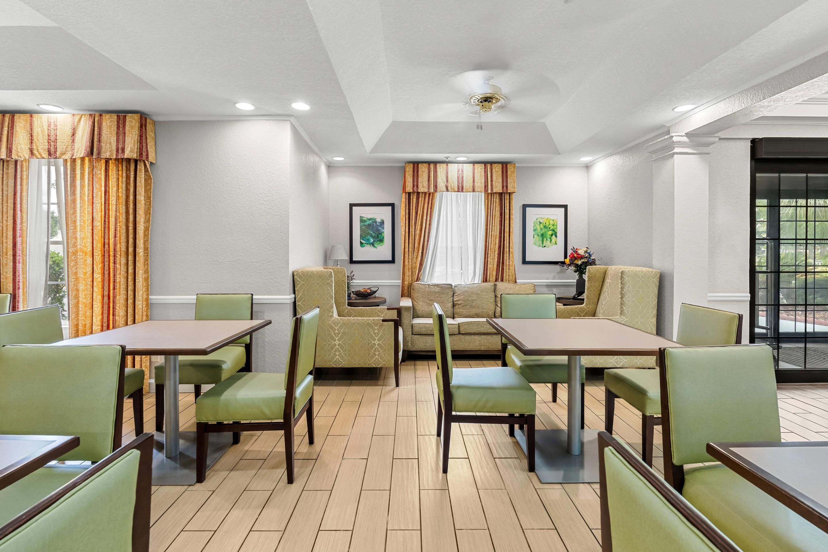 A dining area with tables and chairs, a sofa, and a ceiling fan.