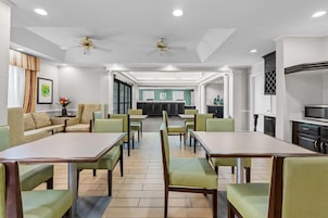 Un comedor de hotel con mesas y sillas, una recepción y una cocina al fondo.