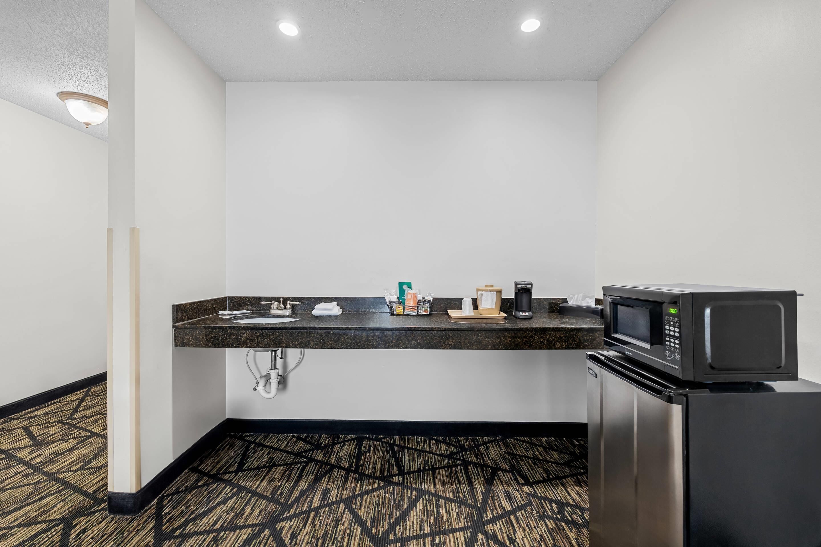 A compact kitchenette with a microwave, coffee maker, and sink.