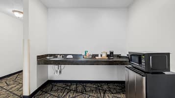 A compact kitchenette with a microwave, coffee maker, and sink.