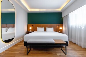 A modern hotel room with a large bed, bedside lamps, a round mirror, and a view of the outdoors through sheer curtains. - Wyndham Sao Paulo Berrini (São Paulo)