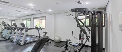 A gym with treadmills, a weight machine, and a mirrored wall.