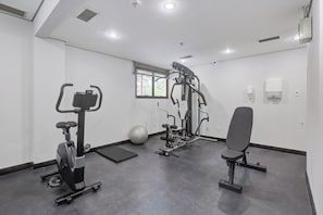 A gym with exercise equipment, a stationary bike, a rowing machine, and a bench. - Wyndham Sao Paulo Berrini (São Paulo)
